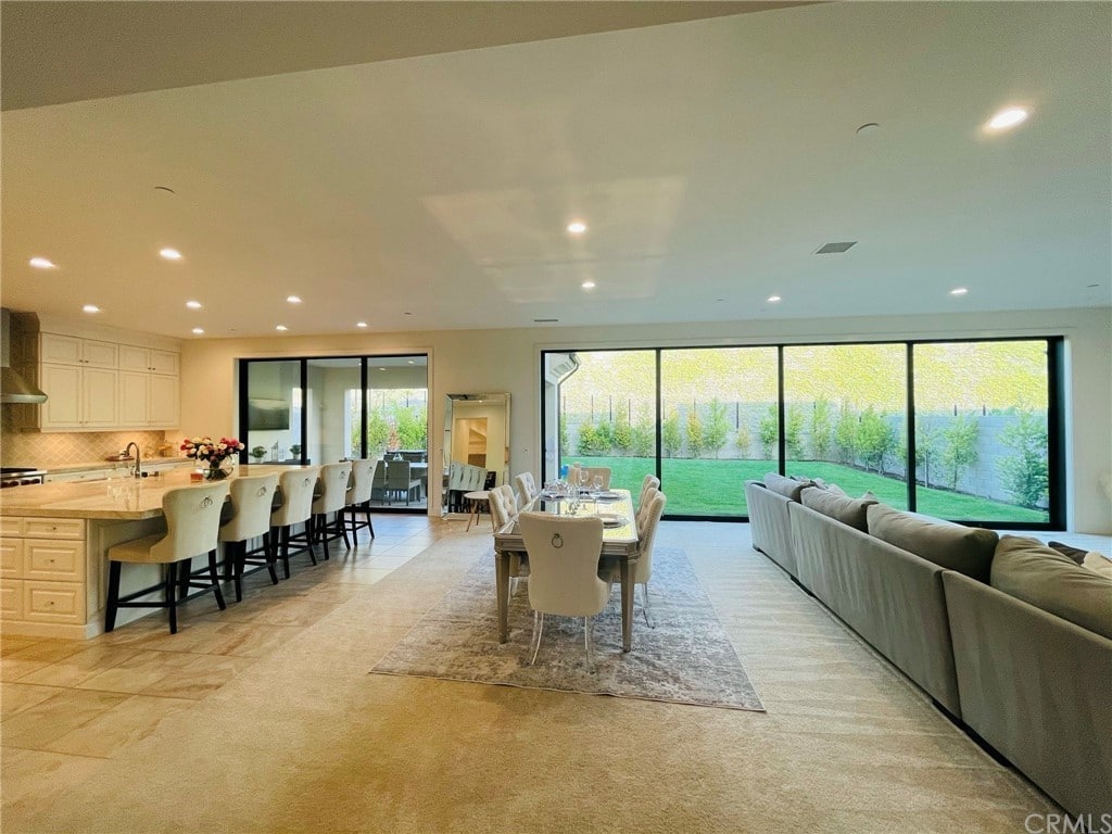 Open Concept Living Room And Kitchen With Wall Of Windows Opening To Backyard