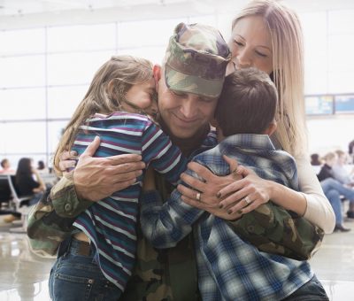 Kids hugging a military soldier