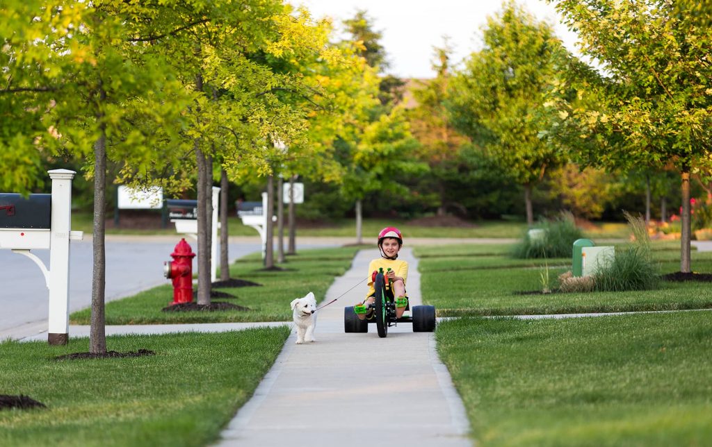 Kid riding a tricycle down a residential street in Norwalk CA